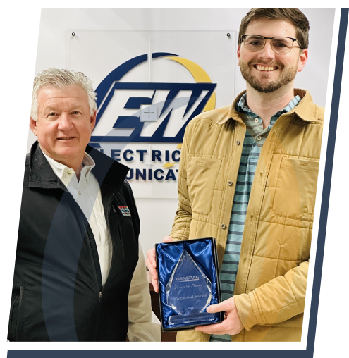 Two employees from E&W Electrical Solutions hold a blue award in front of a wall with their logo